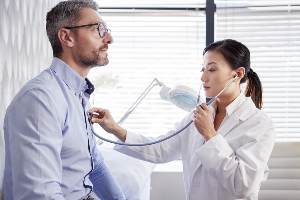 Eine Ärztin hört mt Stethoskop einen Patienten ab.