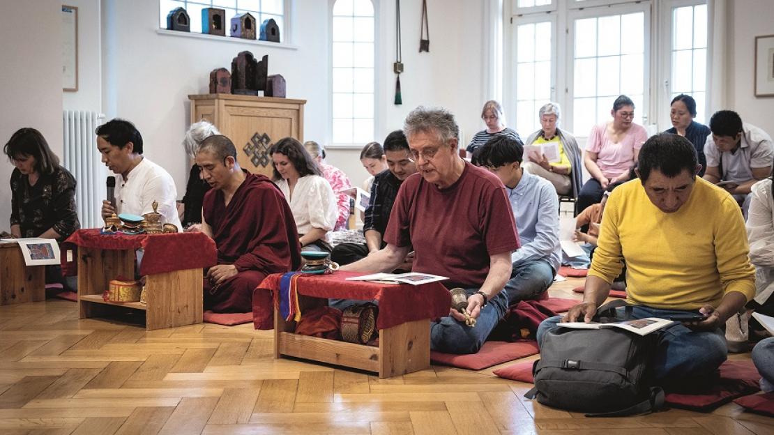 Gläubige zum Saka-Dawa-Düchen-Fest auf dem Boden sitzend und betend im Tibethaus
