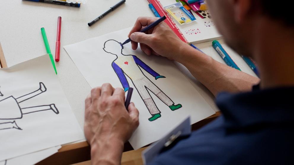 Ein Mann zeichnet eine Figur auf einem Blatt Papier