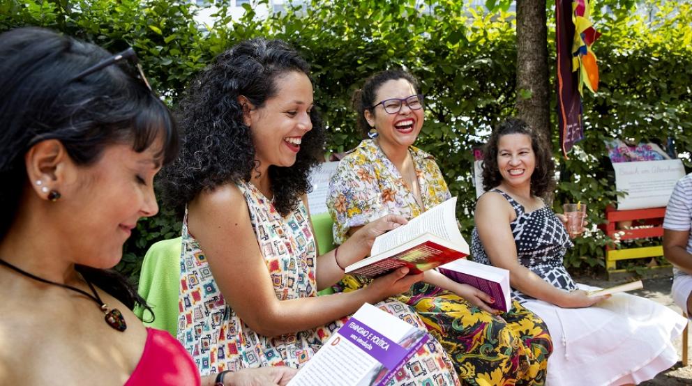 Mehrere Frauen bei einer Lesung sitzend und lachend im Freien